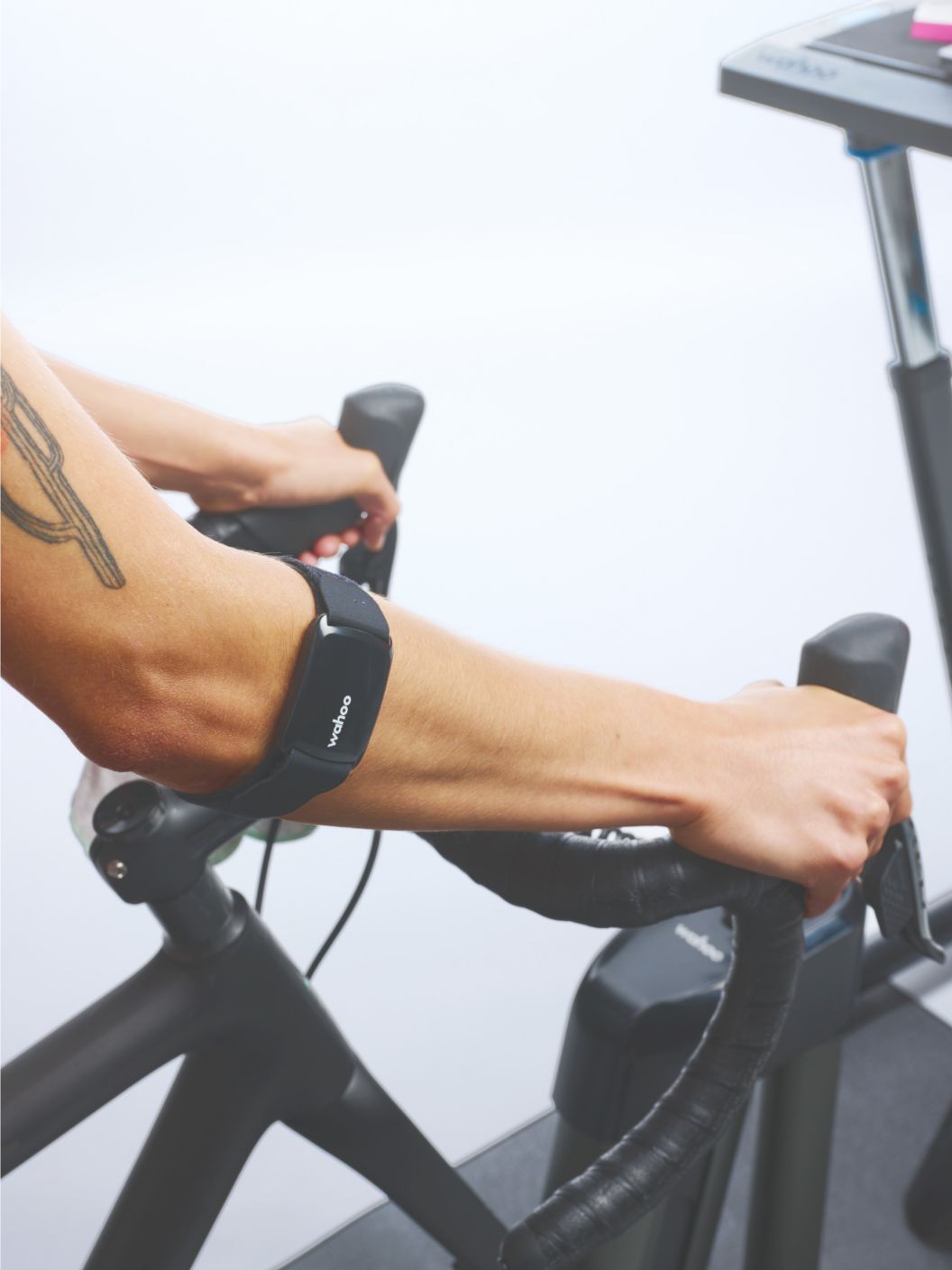 A closeup of Wahoo’s TICKR FIT optical heart rate monitor located on a rider’s arm as they train indoors using Wahoo’s indoor training ecosystem.